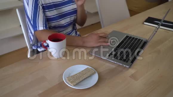 无法辨认的女人在电脑上打字吃零食视频的预览图