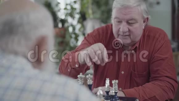 两个成熟的朋友坐在家里下棋高加索老人和邻居在室内愉快地下棋视频的预览图