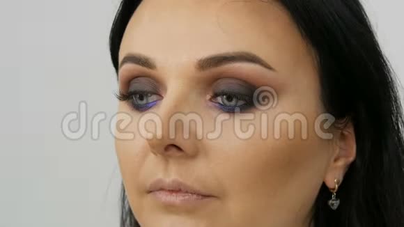 造型师化妆师用一种特殊的刷子在年轻的蓝色美女的脸上涂上粉底视频的预览图