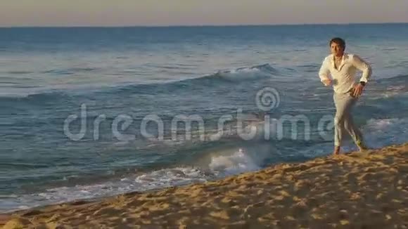 日落时分年轻的赤脚帅哥沿着海滩海岸线奔跑视频的预览图