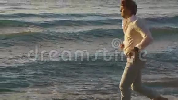 夕阳西下年轻的赤脚男子沿着海滩海岸线奔跑视频的预览图