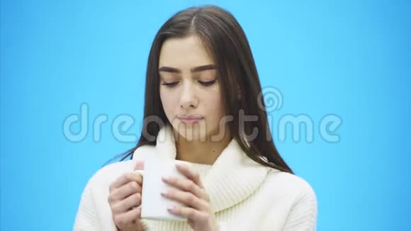 有趣的是一个穿着针织白色毛衣的年轻女人手里拿着一杯白色的咖啡或茶孤立视频的预览图