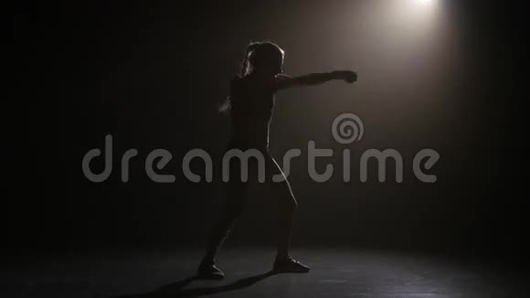 拳王拳击手发出拳打脚踢剪影后方有灯光黑色背景侧视图视频的预览图