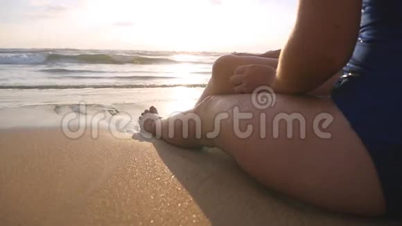 美丽的年轻女子躺在沙滩上的金色沙滩上在暑假旅行中放松坐着的女孩视频的预览图