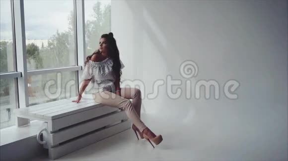 性感漂亮的年轻女人黑发女人坐在窗边视频的预览图