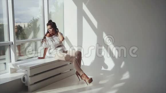 性感的年轻女人黑发女人坐在窗户附近视频的预览图