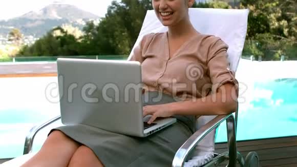 微笑的女商人使用笔记本电脑池边视频的预览图