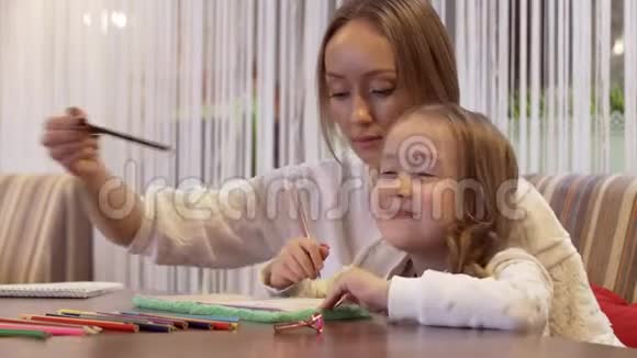 美丽的年轻女子妈妈画她可爱的小女儿视频的预览图
