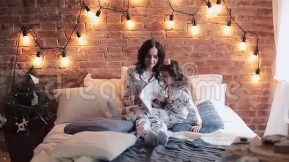 家庭阅读睡觉时间漂亮的年轻母亲在给女儿读一本书视频的预览图