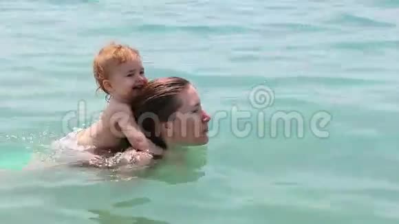 年轻快乐的母亲背着小女孩快乐的家庭在夏季户外游泳视频的预览图