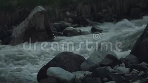 湍急的溪流在高高的石山上覆盖着白雪绿灌木丛视频的预览图
