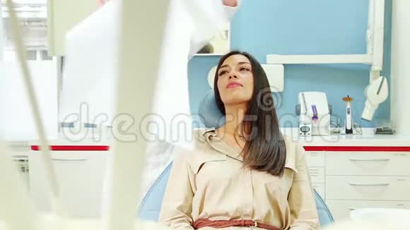 美丽的女人坐在牙科椅上牙医为她准备检查视频的预览图