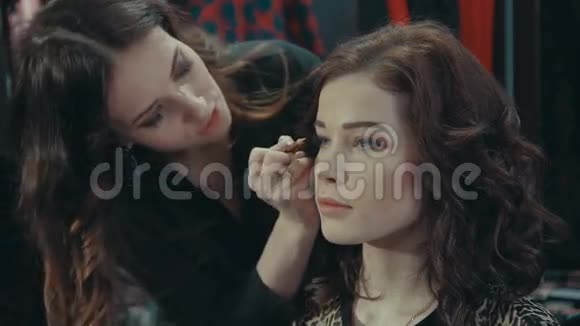 一位年轻的女造型师用眼线贴在一个深色模特的眼皮上视频的预览图