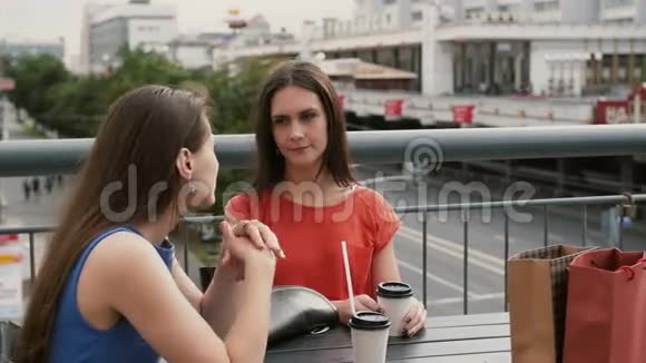 两个喝咖啡的漂亮女人在咖啡馆里交流购物后交谈4k视频的预览图