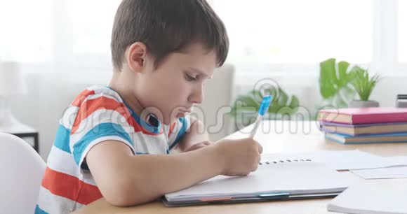 男孩在家里用笔记本写字视频的预览图