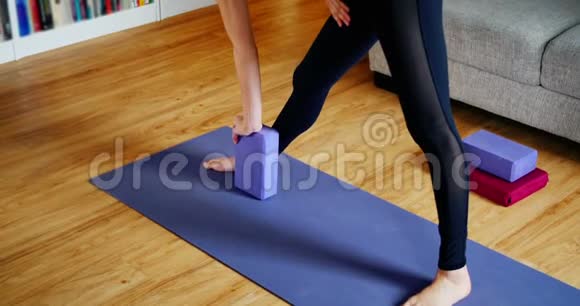 女性在客厅用瑜伽块练习瑜伽视频的预览图