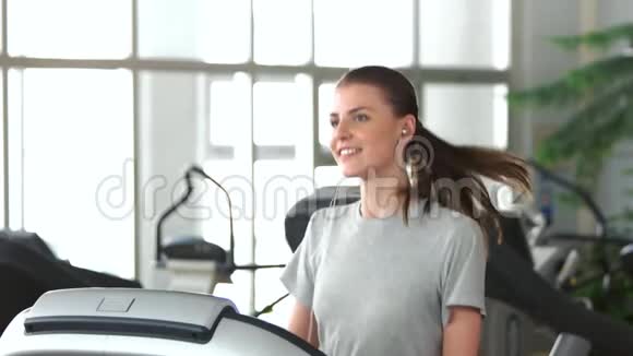 微笑的女孩在跑步机上跑步视频的预览图