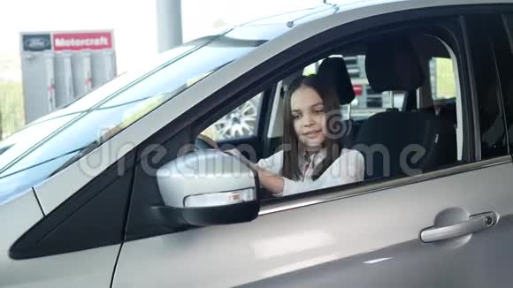 坐在一辆新车上的汽车上美丽的女婴一边看一边微笑视频的预览图