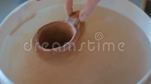 陶工将陶土杯浸入水中视频的预览图