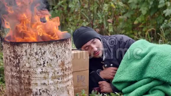一个无家可归的人睡在火边视频的预览图