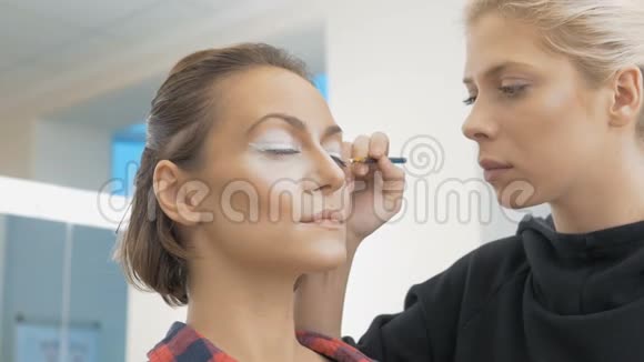 一位专业的化妆师描绘模特的眼睛准备艺术摄影视频的预览图
