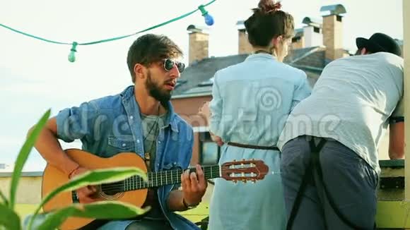 帅哥音乐家在屋顶弹吉他朋友在后台聊天视频的预览图
