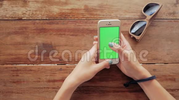 女士使用智能手机木制桌子背景上有绿色屏幕视频的预览图