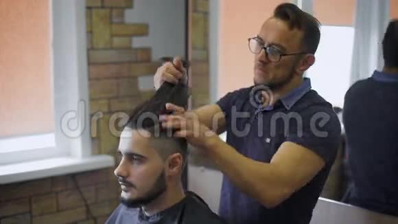兰伯克风格理发店男理发师穿着格子衬衫梳着一个男客户的头发视频的预览图