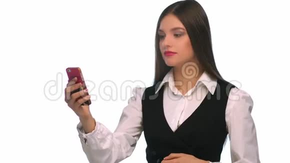 年轻漂亮的女人看着欣赏她的脸在口袋镜子前手机摄像头隔离在白色背景上视频的预览图
