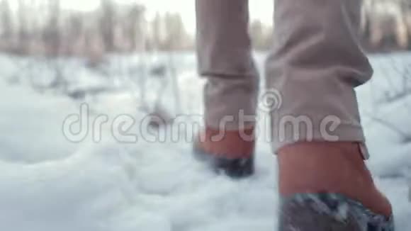 摄像机追踪白天在雪地里行走的人的腿视频的预览图