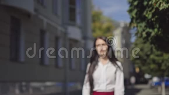 阳光明媚的一天美丽的黑发商界女性在一条城市街道上打电话视频的预览图