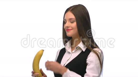 穿着西装穿着白色背景的黑发女孩在吃一根有声音的香蕉视频的预览图