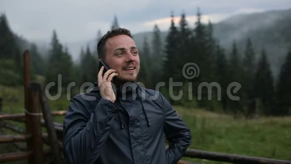 一个年轻人晚上在山里打电话在雾中的森林周围视频的预览图