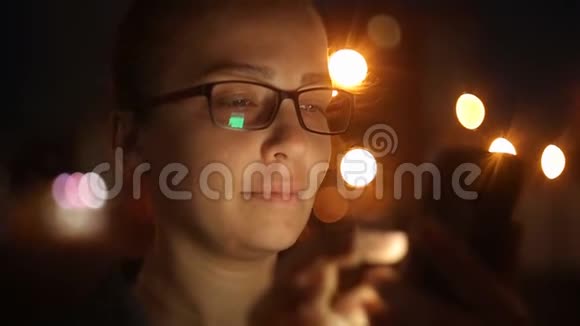 年轻美丽的白种人妇女使用智能手机在城市夜晚手持户外微笑面对视频的预览图