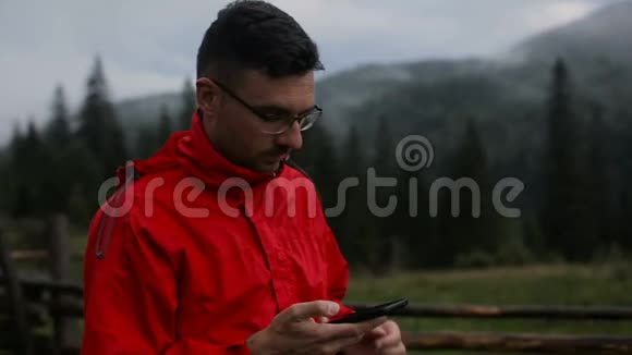一个年轻人晚上在山里打电话在雾中的森林周围视频的预览图