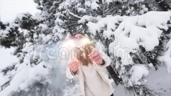 年轻积极的女孩在冬天的森林里下雪圣诞节和火花视频的预览图