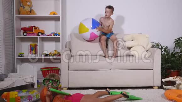 一个女孩戴着水下面具脚蹼在房间里游泳男孩在沙发上玩充气球视频的预览图