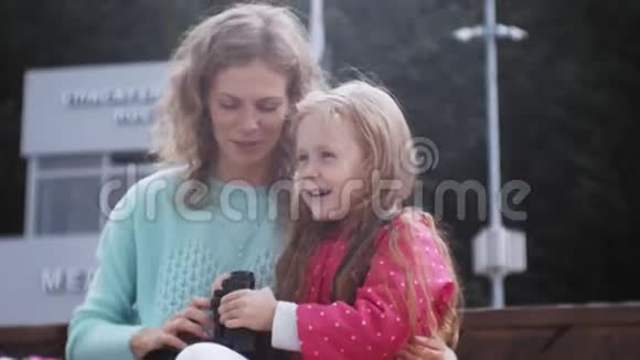 一个女人带着女儿在海滩上看望远镜视频的预览图