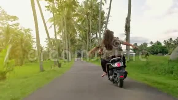 日落时分一对幸福的夫妇在热带公路上骑摩托车绊倒户外拍摄的年轻夫妇骑摩托车男子视频的预览图