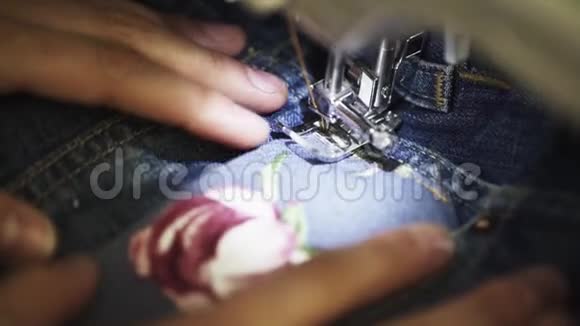 女裁缝手用缝纫机将玫瑰图案缝合到牛仔布上视频的预览图