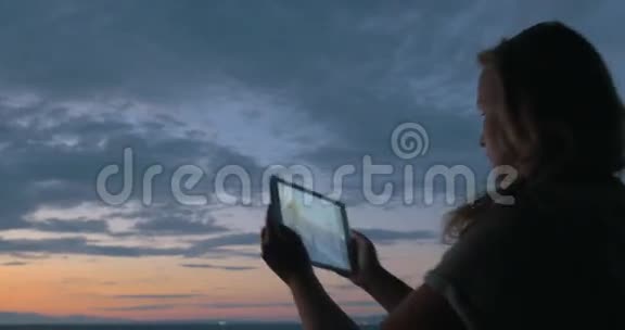 女人用垫子在黄昏中拍海和天空的照片视频的预览图