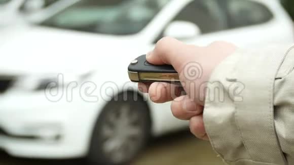 手按遥控器在停车场上的车背景模糊特写复制空间视频的预览图