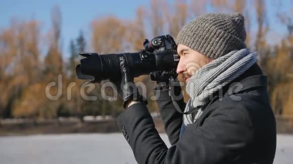 黑色公园配有专业照相机的年轻摄影师拍摄美丽的冬季公园视频的预览图