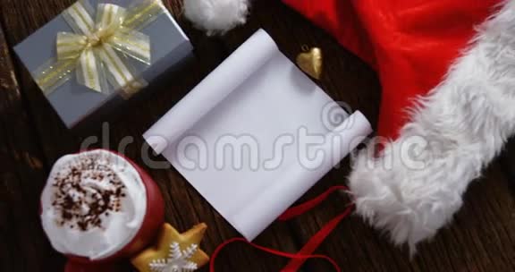 带圣诞老人帽的白纸和木板上的礼品盒视频的预览图