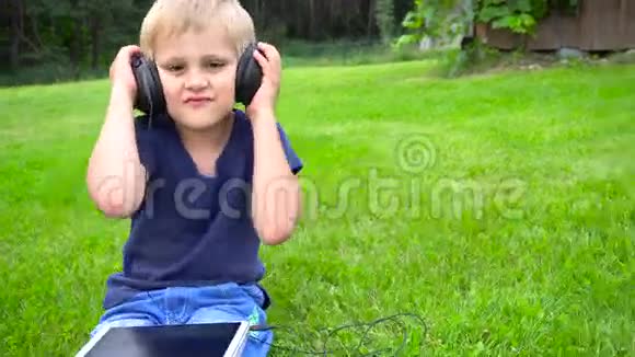 男孩在户外平板电脑上听音乐视频的预览图