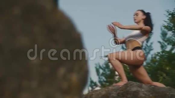 美丽强壮的黑发女人穿着运动服在悬崖边户外练习瑜伽放松夜空视频的预览图
