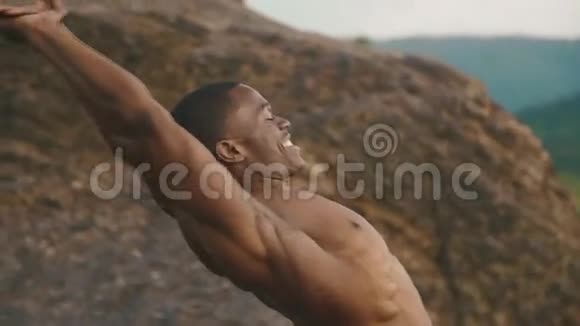 非洲裔美国健美运动员的特写裸露的躯干伸展室外落基山景观背景视频的预览图