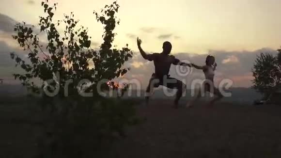 运动型肌肉混合赛跑运动员在山顶日落时做体操的剪影视频的预览图