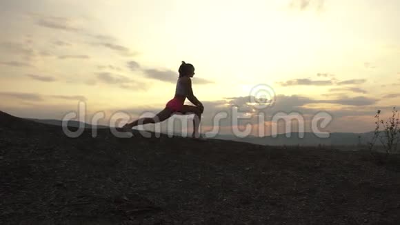 适合肌肉发达的女人在日落时在户外伸展的剪影健身理念视频的预览图
