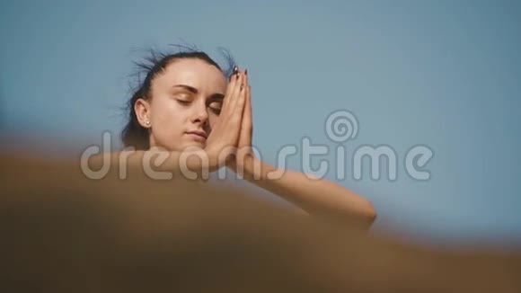 可爱的黑发女人在岩石山峰上练习瑜伽晴空背景视频的预览图